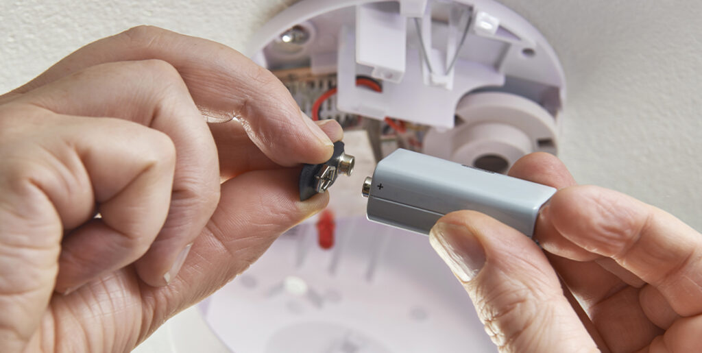 Person connecting battery to smoke alarm.