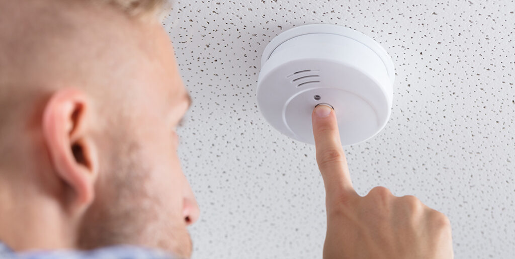 Worker testing to see that the new hardwired smoke alarm is working.